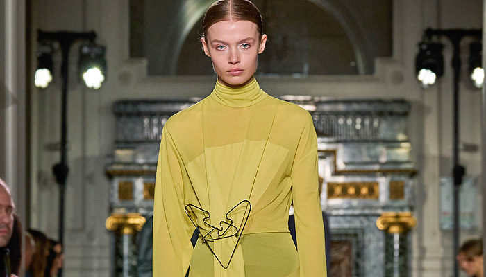 Victoria Beckham 2024-2025 Fall Autumn Winter Womens Runway Looks - Paris Fashion Week PFW - Japanese Denim Jeans High Collar Funnel Neck Turtleneck Pencil Skirt High Waist Wide Leg Flare Knit Sweater Jumper Asymmetrical Deconstructed Chain Fringes Wire Hanger Brooch Dress Coils Tights Stockings Silk Blazer Jacket Strapless Leather Aviator Trench Coat Nautical Hood Boxy Frankenstein Shoulders Pantsuit Sheer Tulle Gown Loafers Handbag